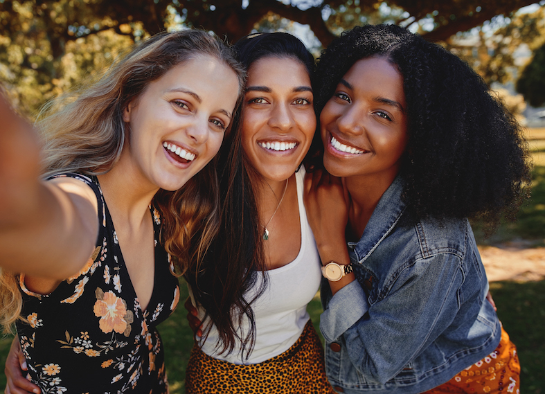 Close-up self portrait of smiling young multiethnic female friends taking selfie in the park - women taking a selfie in the park on a bright day