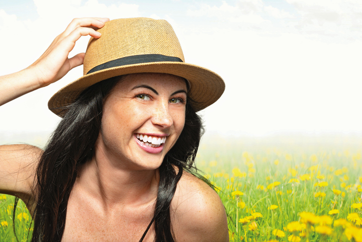 A woman smiling in a field of yellow flowers.