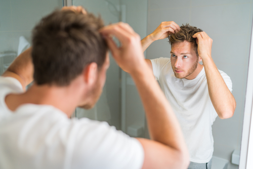 Man checking his hair in the mirror for hair loss